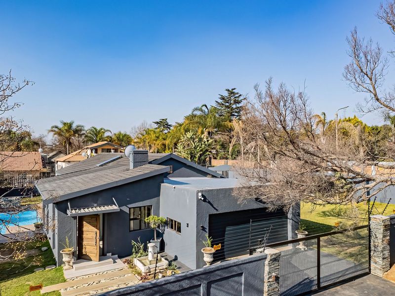 Aerial view of a modern grey-painted house featuring a swimming pool, attached garage, and landscaped garden area.