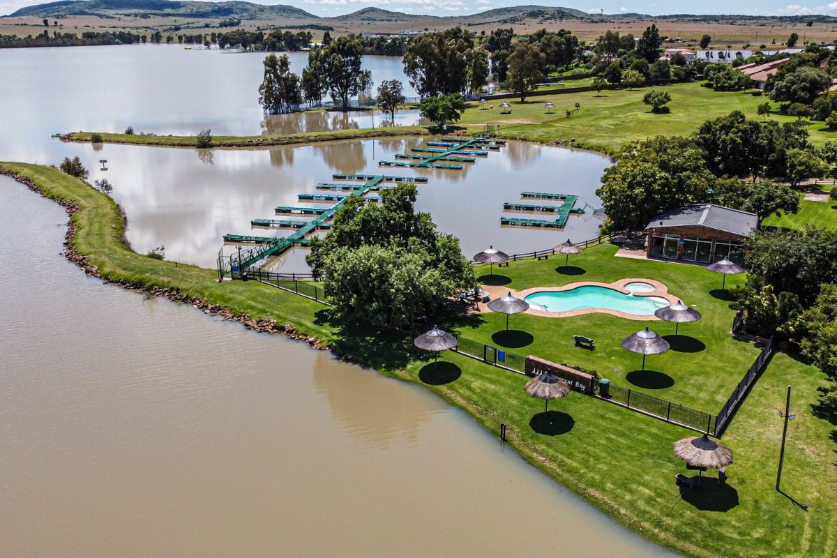 Aerial view of a waterfront estate featuring a swimming pool, landscaped gardens, and a private boat jetty on the lake.