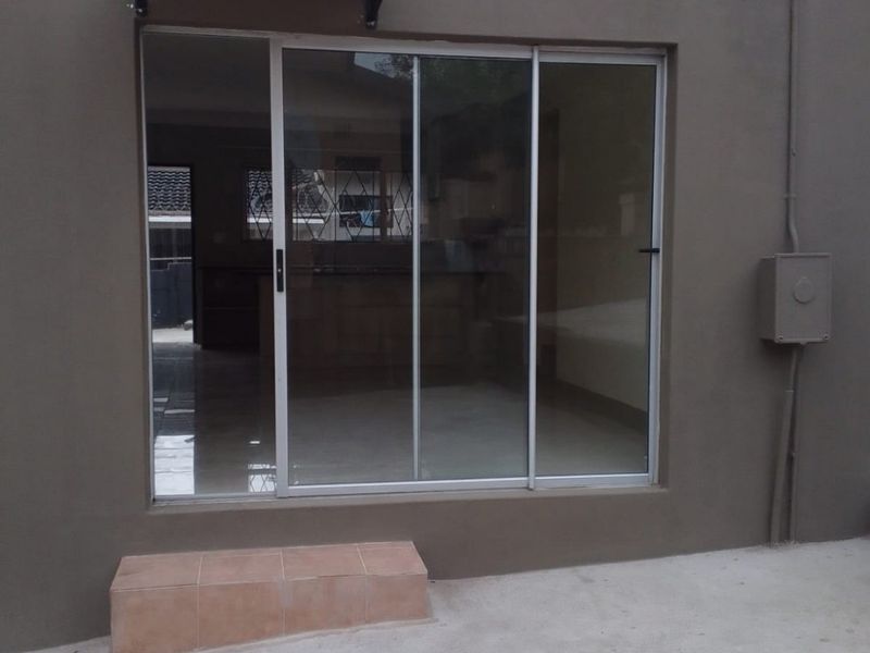 Rear exterior view featuring a sliding glass door, a tiled step, and exterior wall-mounted electrical and lighting fixtures.