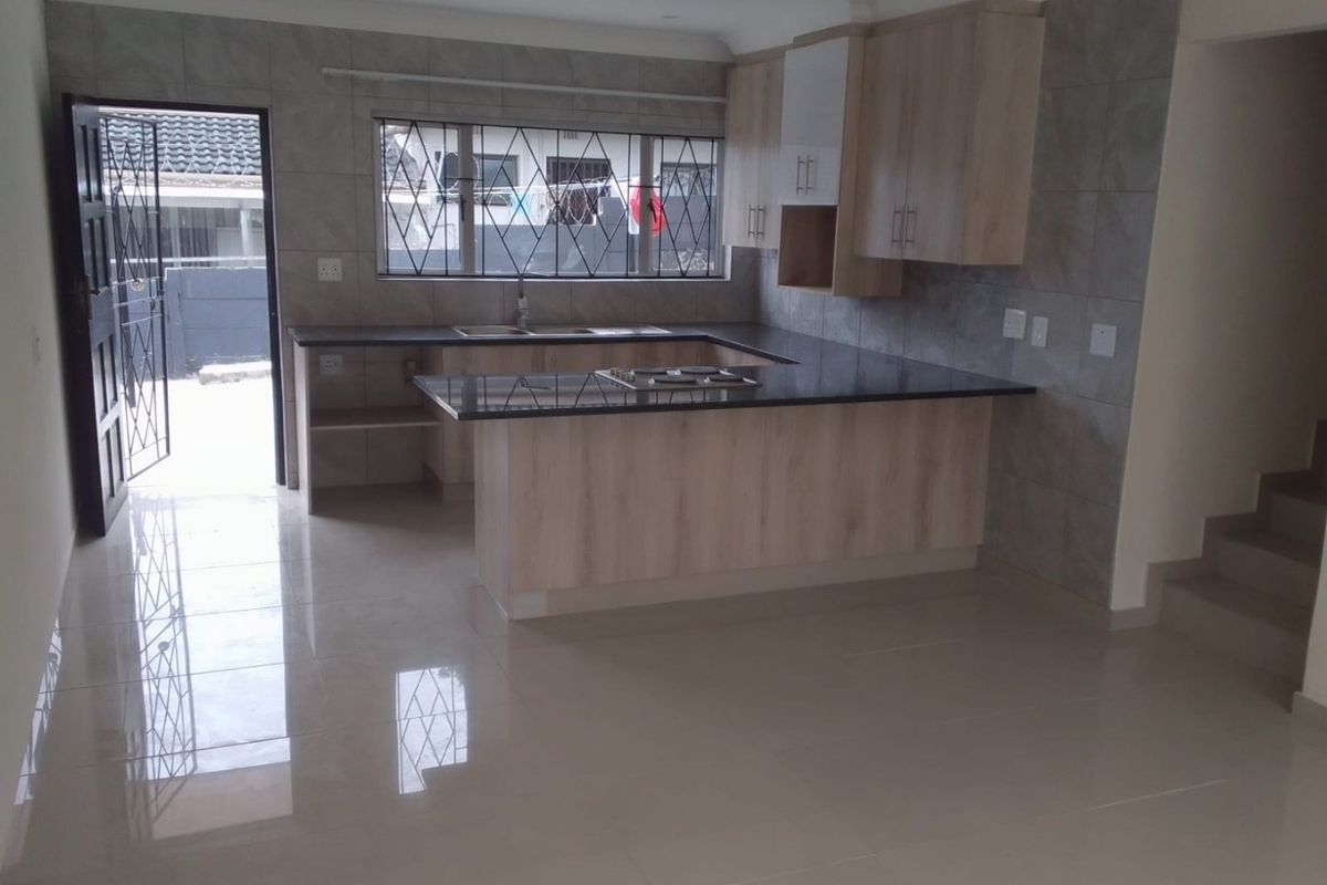 Modern kitchen featuring light wood cabinetry, granite countertops, integrated hob, and tiled finishes, offering a clean and functional workspace.