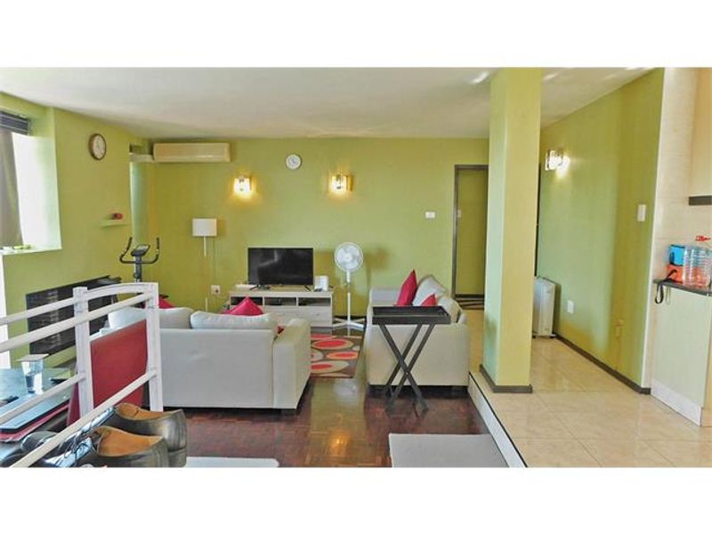 Open plan living area featuring a combination of parquet and tiled flooring, wall sconce lighting, and an integrated air conditioning unit.