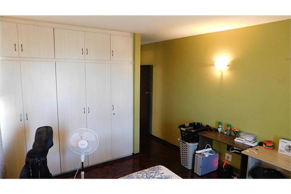 Bedroom featuring extensive built-in cupboard storage, parquet flooring, and a wall-mounted light fixture.