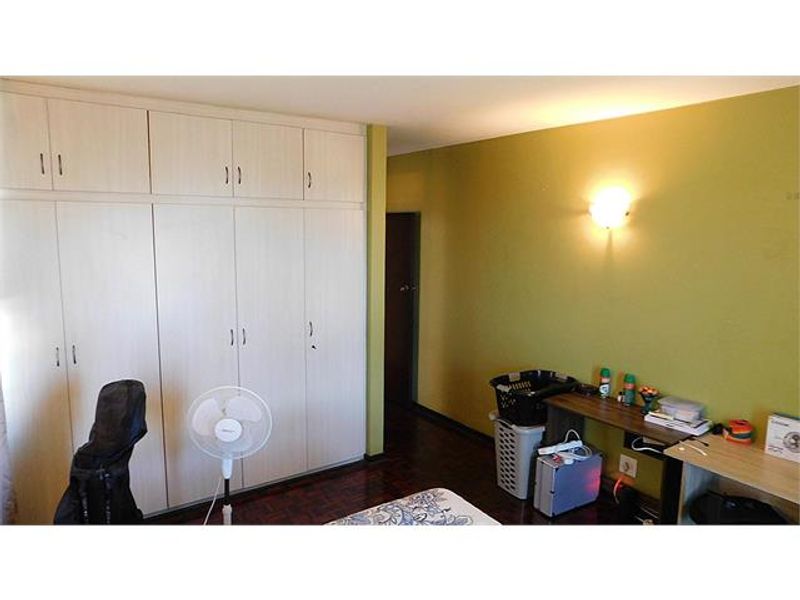 Bedroom featuring extensive built-in cupboard storage, parquet flooring, and a wall-mounted light fixture.
