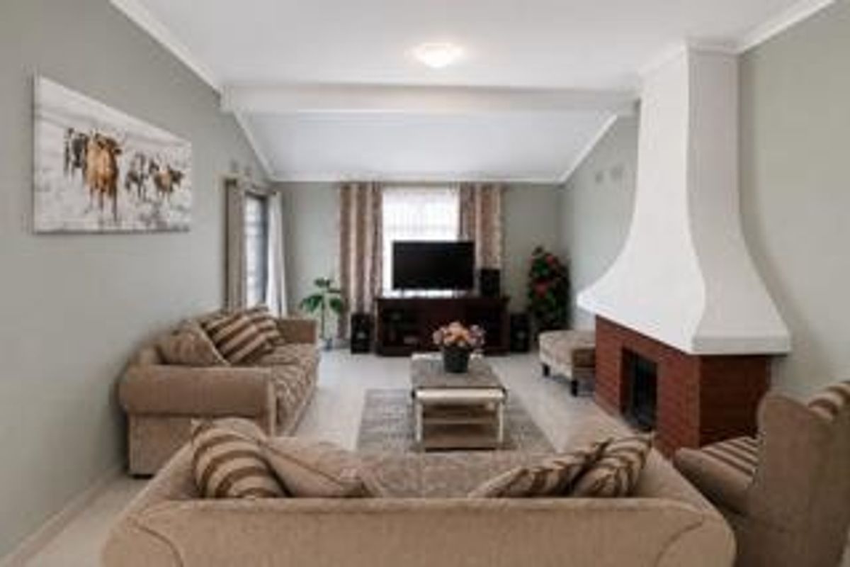 A comfortable living room featuring a prominent brick fireplace with a white mantle and a vaulted ceiling, creating a warm and inviting atmosphere.