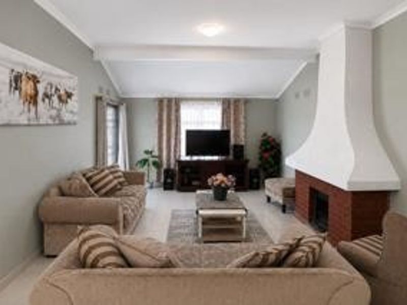 A comfortable living room featuring a prominent brick fireplace with a white mantle and a vaulted ceiling, creating a warm and inviting atmosphere.
