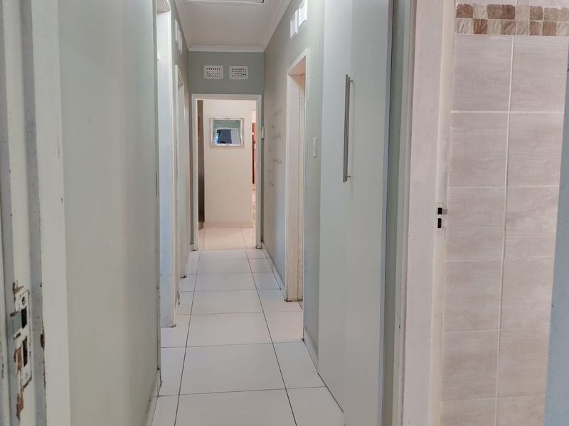 A functional hallway featuring tiled flooring and built-in storage cupboards, providing access to multiple rooms within the home.
