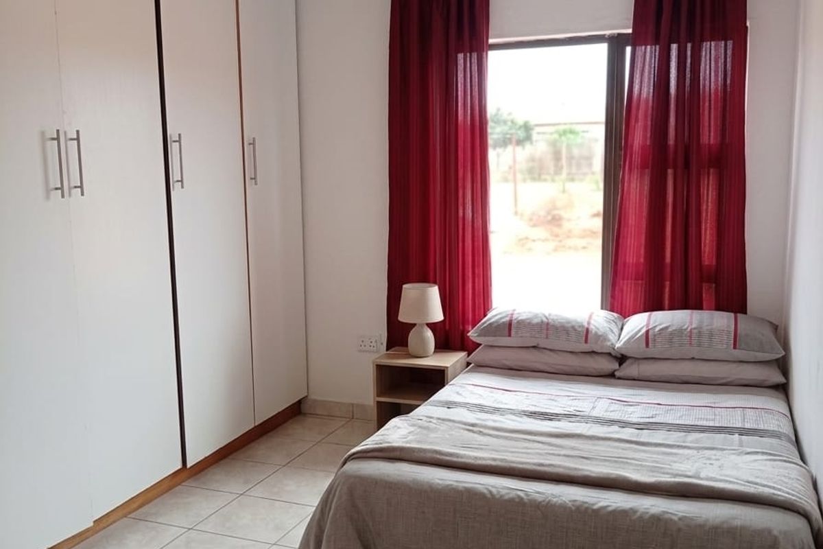 A functional bedroom featuring built-in cupboards, tiled flooring, and a PVC ceiling, providing a clean and practical living space.