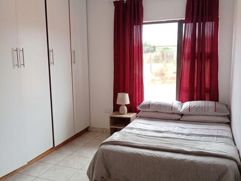 A functional bedroom featuring built-in cupboards, tiled flooring, and a PVC ceiling, providing a clean and practical living space.