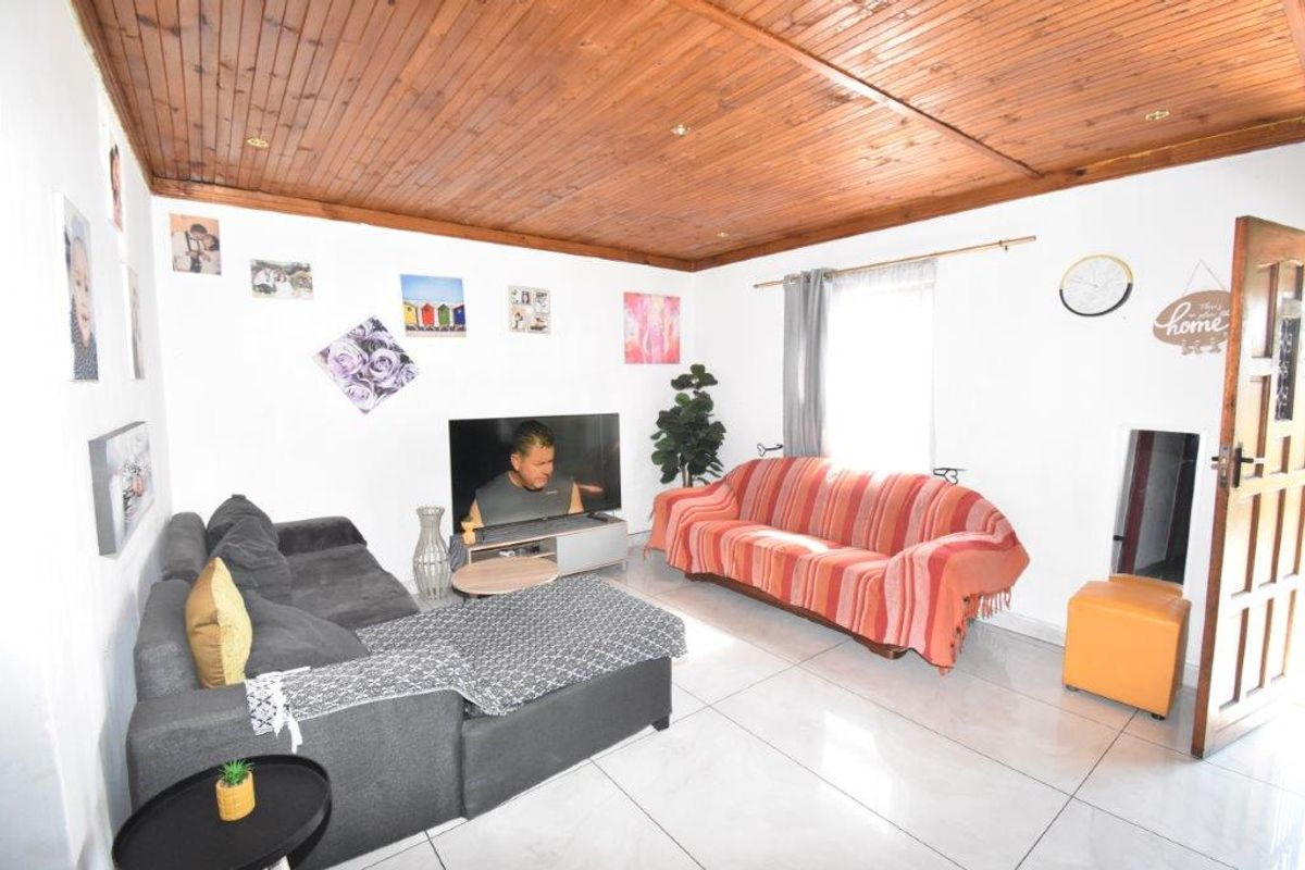 A living room featuring a timber tongue and groove ceiling with recessed downlights and tiled flooring.
