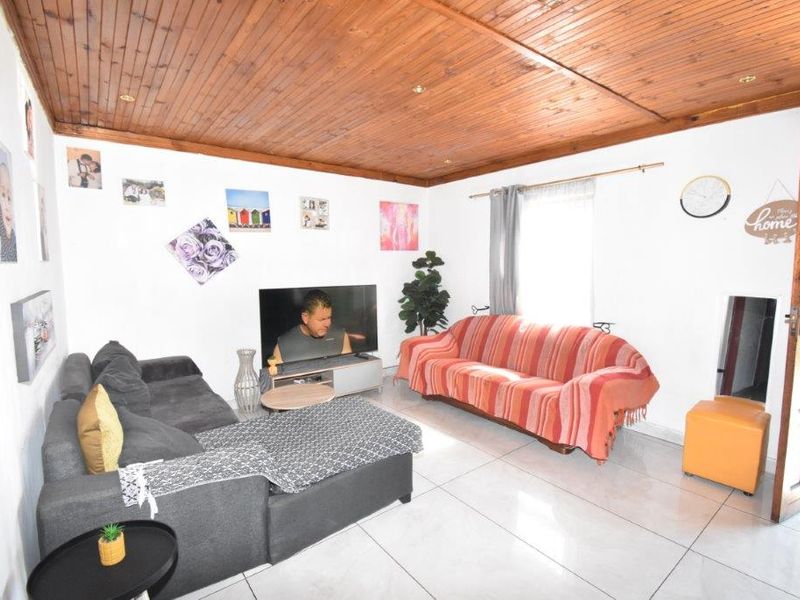 A living room featuring a timber tongue and groove ceiling with recessed downlights and tiled flooring.