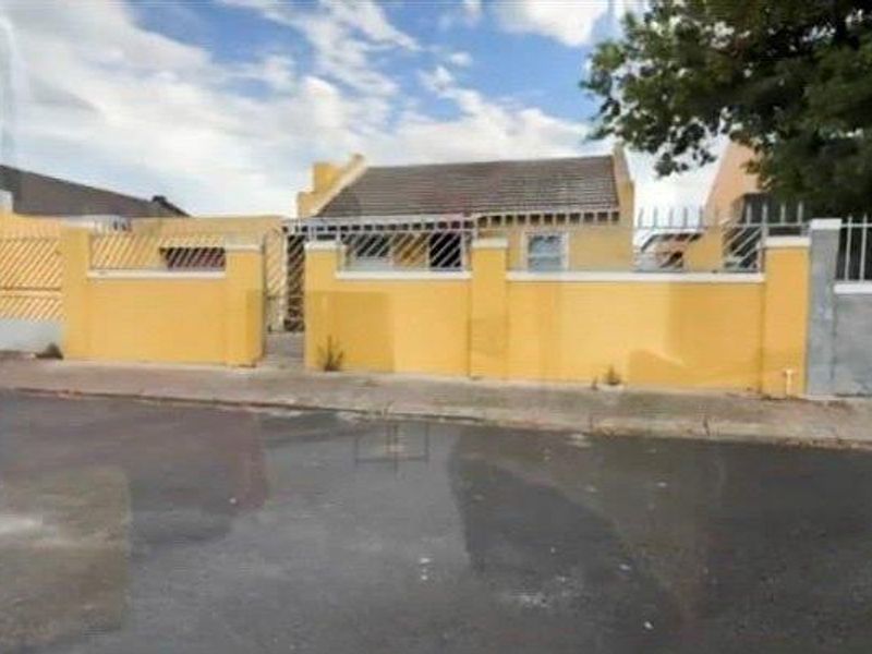 Front exterior view of a residential property featuring a perimeter wall with metal security fencing and a gated entrance.