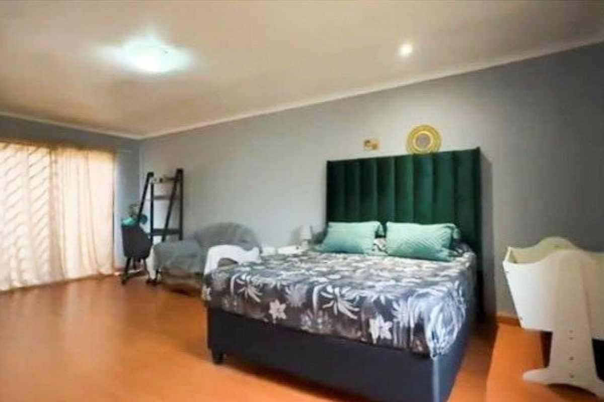 Spacious bedroom featuring laminate flooring, recessed lighting, and a large sliding glass door providing access to the exterior.