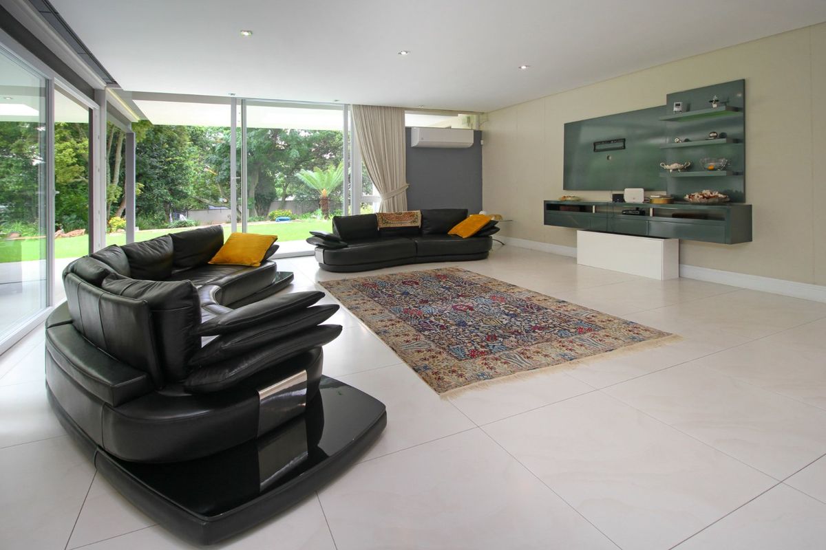 Spacious living room featuring large sliding glass doors opening to the garden, tiled flooring, recessed lighting, and built-in wall cabinetry.