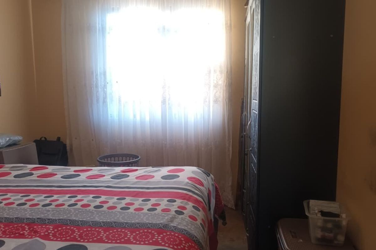 A standard bedroom featuring a window with sheer curtains, providing natural light to the space.