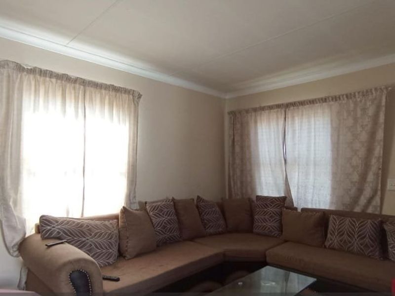 A living room featuring neutral wall finishes, cove cornicing, and natural light through multiple windows.