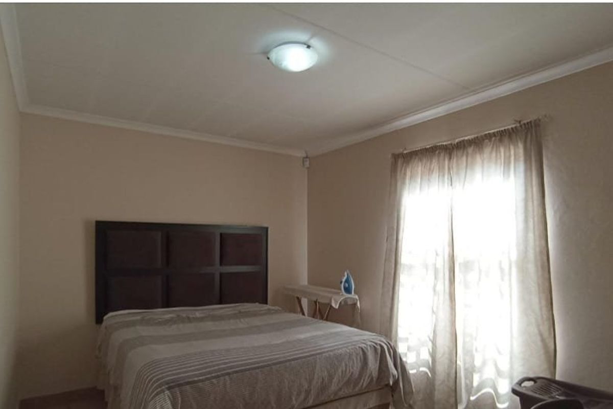 A standard bedroom featuring neutral wall tones, ceiling cornicing, and a central light fixture, providing a functional and well-lit sleeping space.