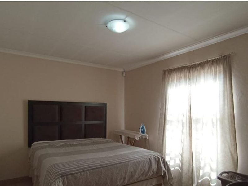 A standard bedroom featuring neutral wall tones, ceiling cornicing, and a central light fixture, providing a functional and well-lit sleeping space.