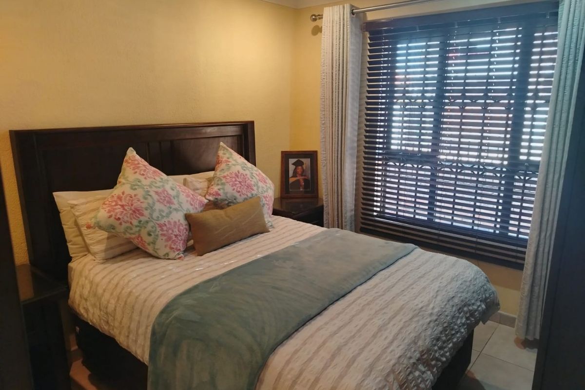 A cozy bedroom featuring tiled flooring, crown molding, and venetian blinds, providing a functional and comfortable sleeping space.