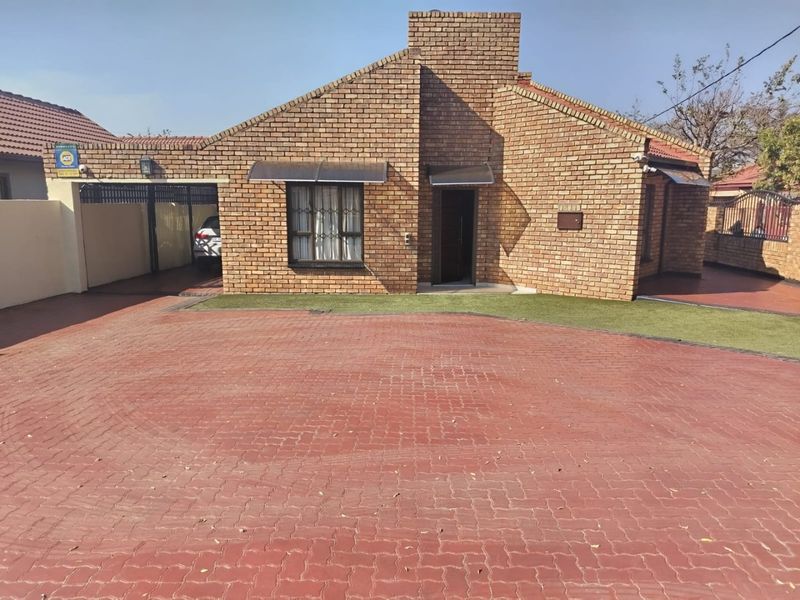 Front view of a face brick house featuring a spacious paved driveway, integrated carport, and low-maintenance artificial lawn.