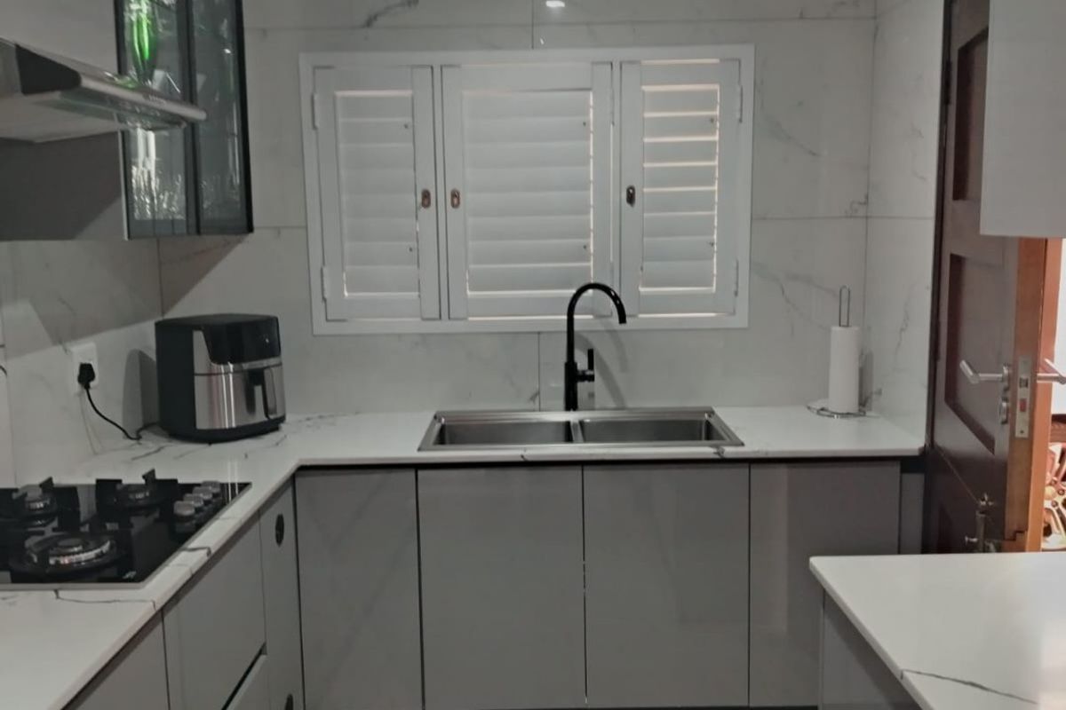Modern kitchen featuring sleek grey cabinetry, marble-look countertops, gas hob, extractor fan, and a double sink with a contemporary black mixer tap.
