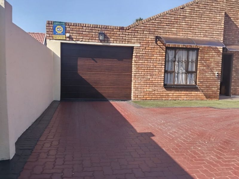 Front exterior view of a face brick house featuring a paved driveway, a single garage, and a secure entrance.