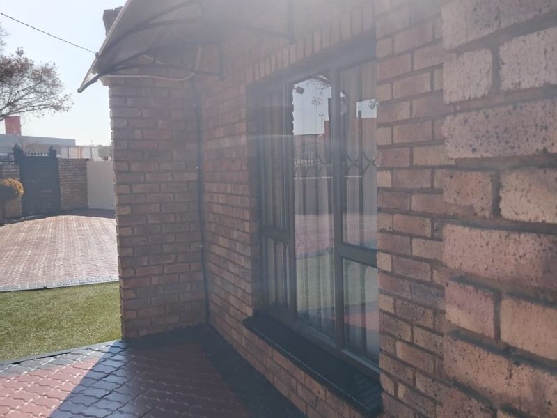 A view of the front exterior featuring face brick walls, a paved driveway, and an installed awning over the window.