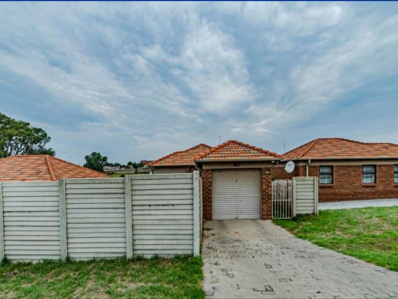 Front exterior view of a brick house featuring a tiled roof, single garage, paved driveway, and precast concrete boundary wall.