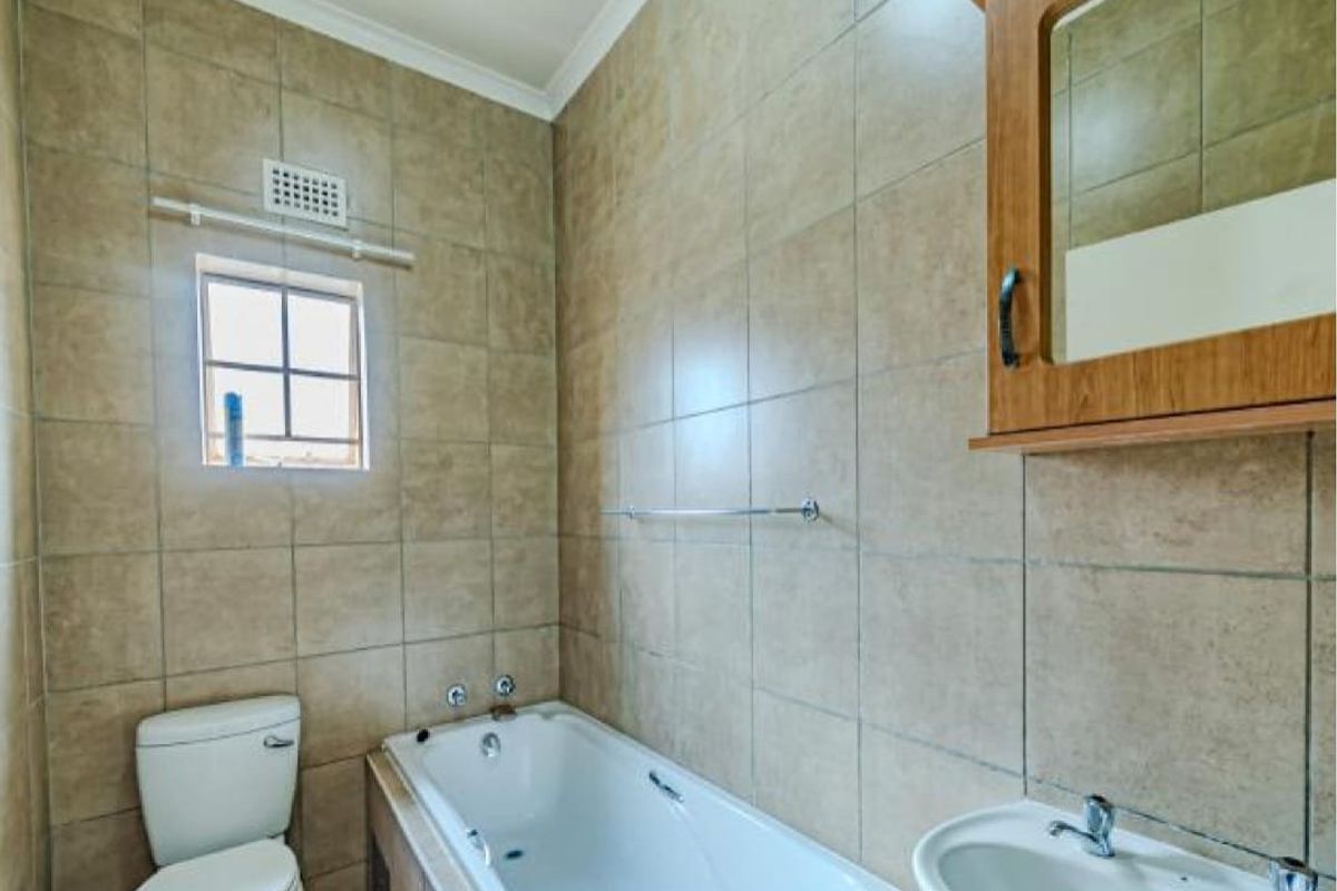A functional bathroom featuring tiled walls, a bathtub, a pedestal basin, and a wall-mounted medicine cabinet.