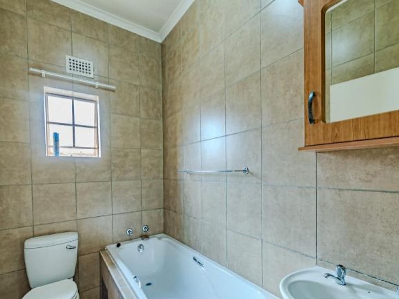 A functional bathroom featuring tiled walls, a bathtub, a pedestal basin, and a wall-mounted medicine cabinet.