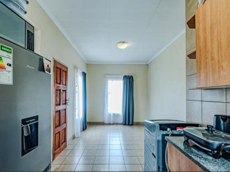 A functional kitchen area featuring tiled flooring, built-in cabinetry with granite countertops, and a dedicated space for a refrigerator.