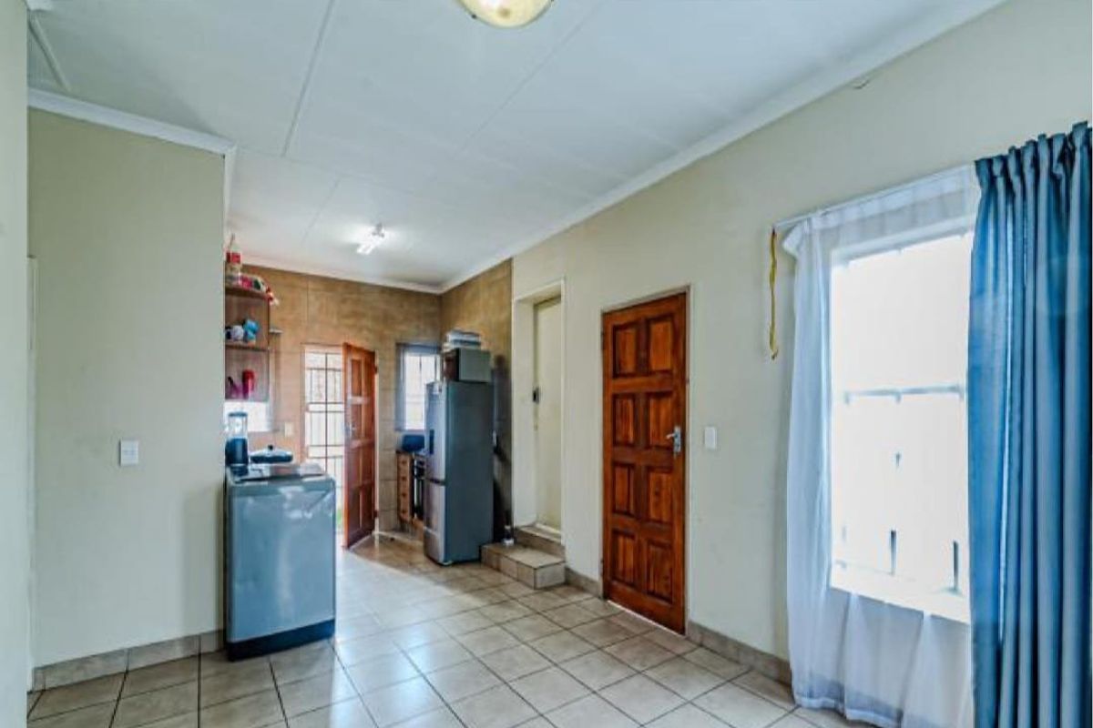 A functional kitchen area featuring tiled flooring, a wooden door, and natural light from a side window.