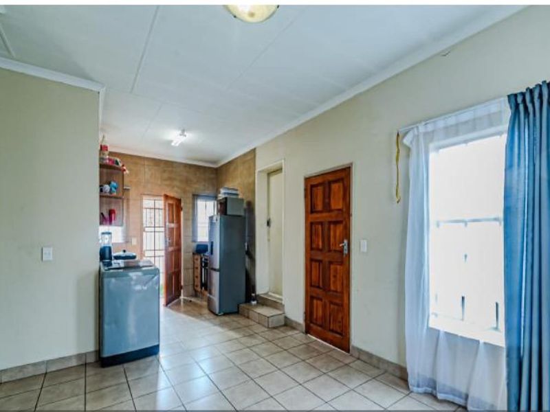 A functional kitchen area featuring tiled flooring, a wooden door, and natural light from a side window.