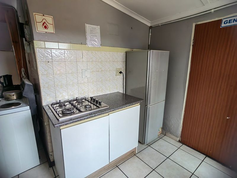 Compact kitchen area featuring a gas hob, tiled splashback, base cabinetry, and tiled flooring, requiring some cosmetic updates to the wall finishes.