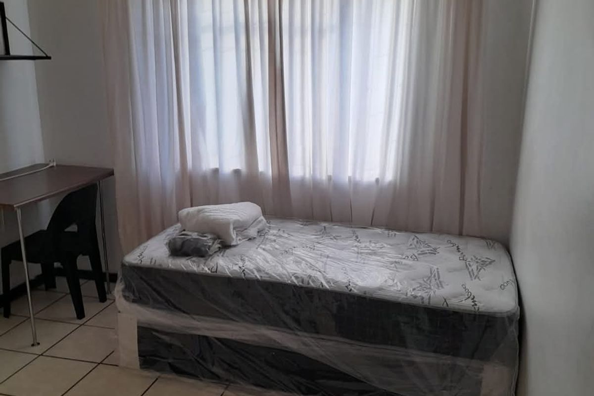 A functional bedroom featuring tiled flooring and a ventilation grille, providing a simple and clean living space.