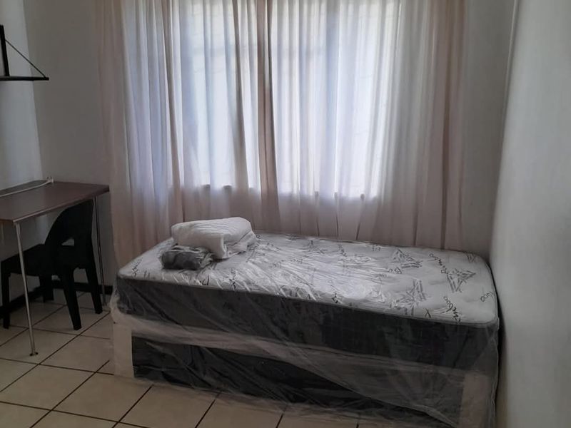 A functional bedroom featuring tiled flooring and a ventilation grille, providing a simple and clean living space.