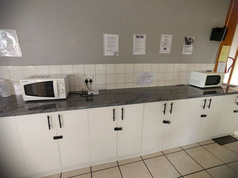 A functional kitchen prep area featuring white cabinetry, stone-look countertops, and tiled backsplash, suitable for renovation or modernization.