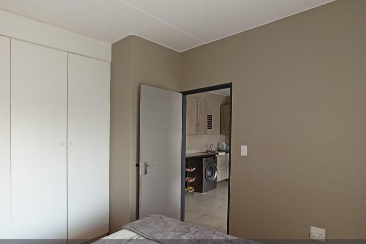 A bedroom featuring built-in cupboards with a view into an adjacent kitchen area.
