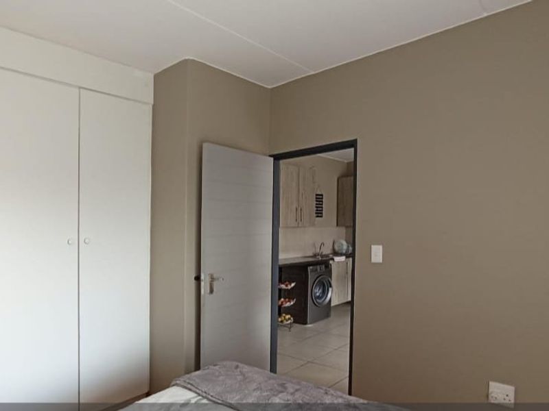 A bedroom featuring built-in cupboards with a view into an adjacent kitchen area.