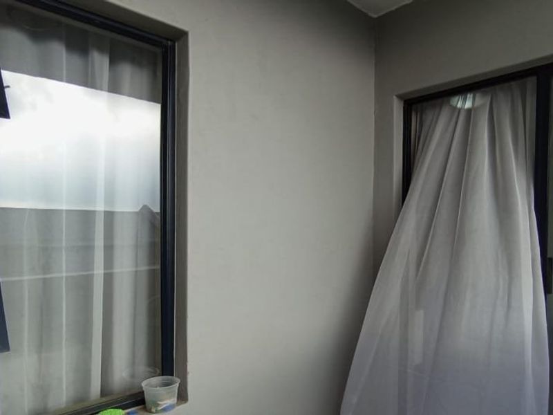 A covered balcony area featuring modern dark aluminium window frames and a sliding glass door, providing a clean and functional outdoor transition space.
