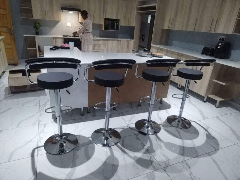 Modern kitchen featuring a central island, extensive built-in cabinetry, integrated appliances, and polished marble-look tiled flooring.