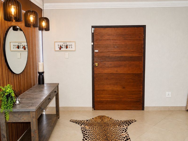 A welcoming entrance hall featuring a solid timber front door, decorative timber slat wall paneling, and neutral tiled flooring.