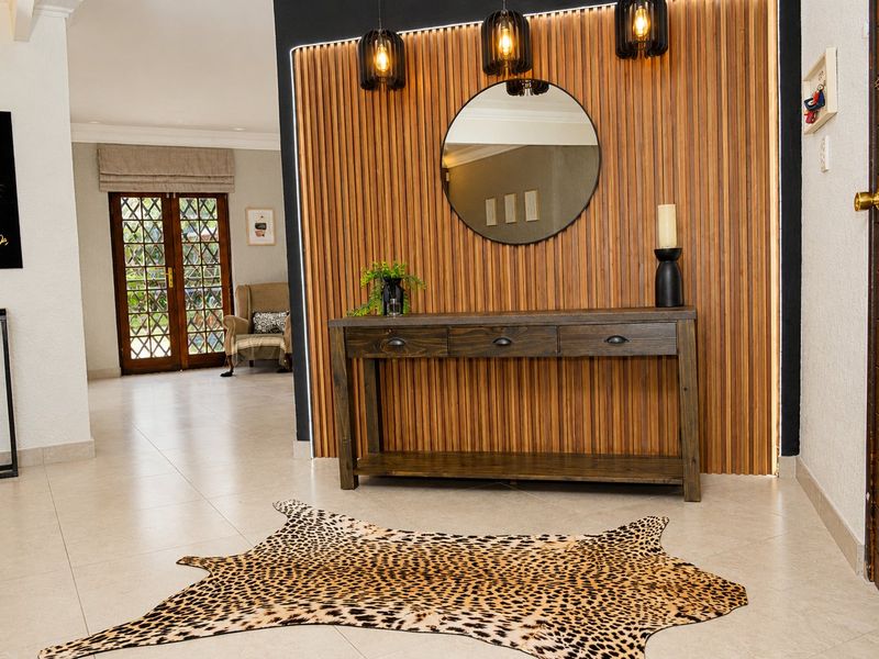 A modern entrance hall featuring a striking timber slat feature wall with integrated LED lighting, tiled floors, and contemporary pendant fixtures.