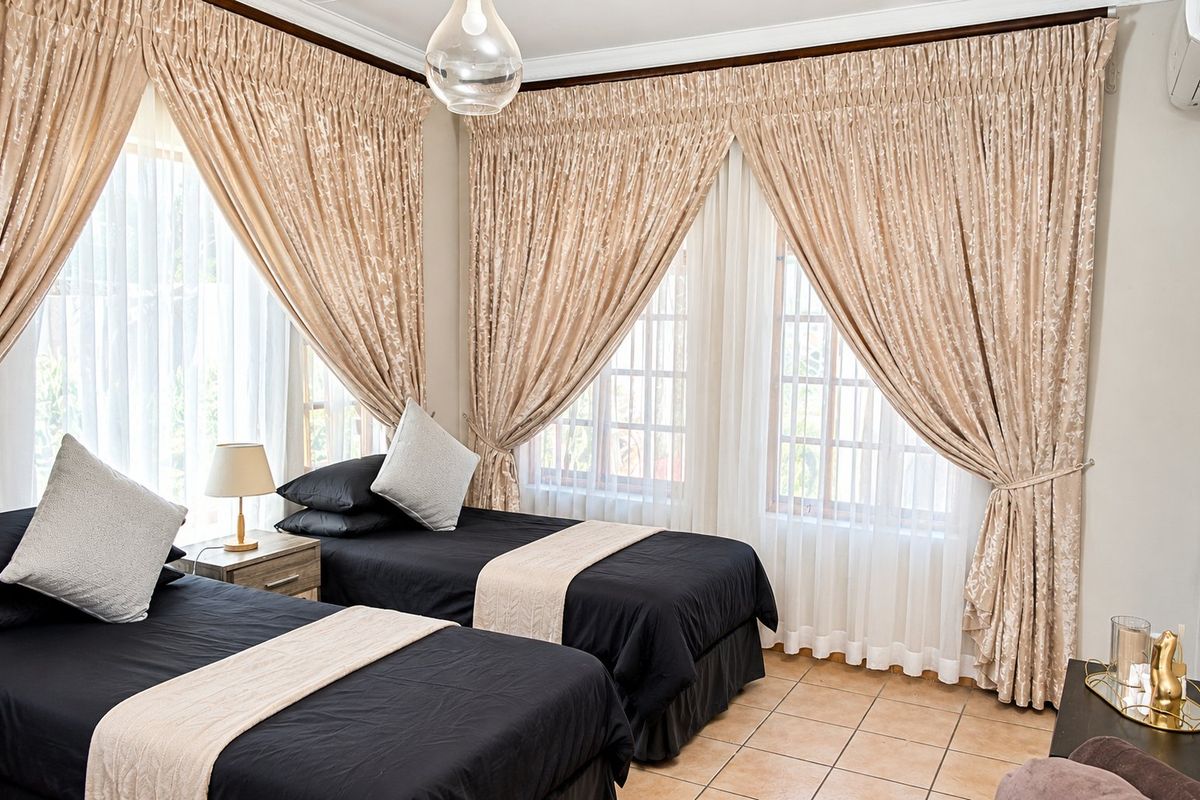 A well-lit bedroom featuring tiled flooring, large windows with timber frames, and decorative cornicing.