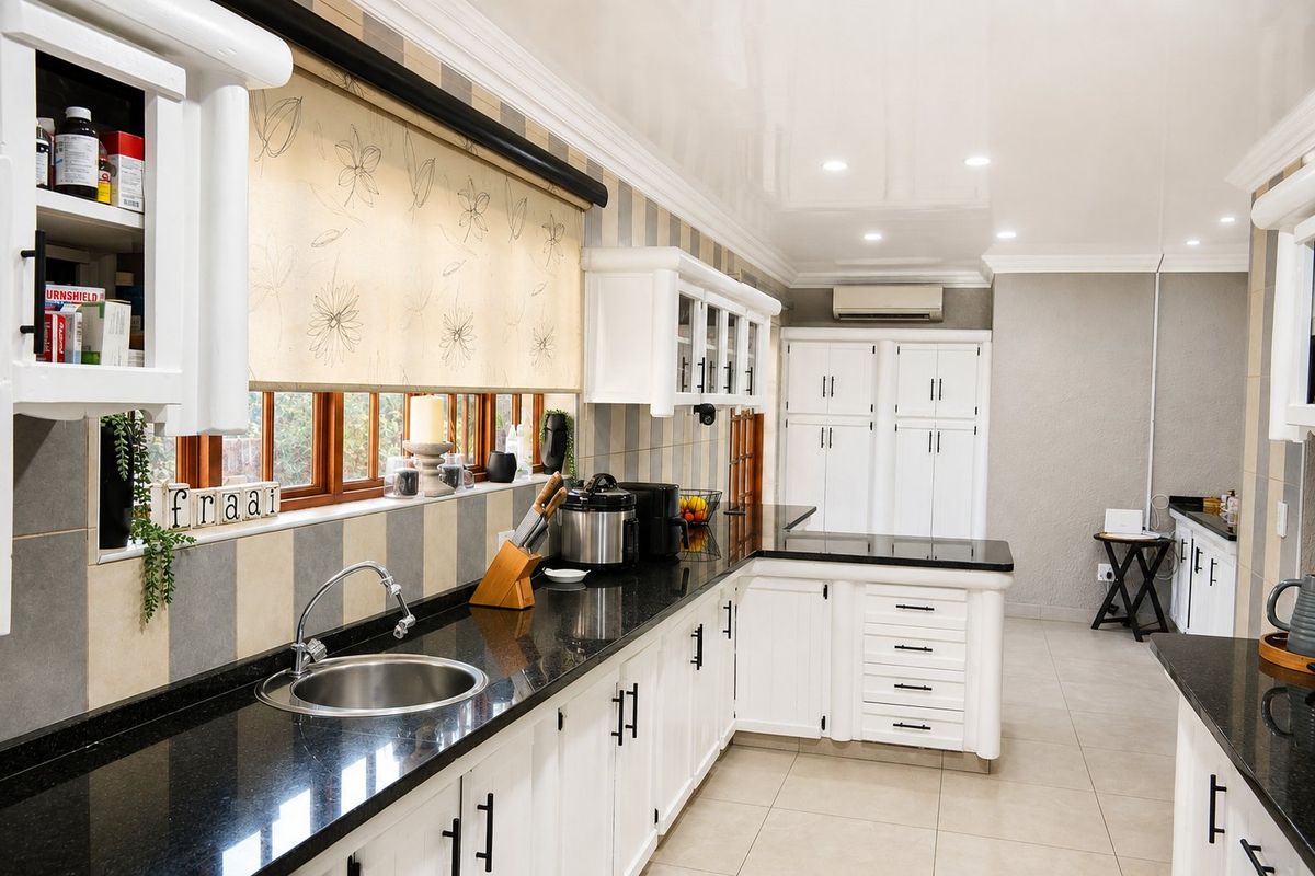 A well-maintained kitchen featuring granite countertops, ample white cabinetry, tiled backsplash, and recessed lighting, offering a clean and functional workspace.