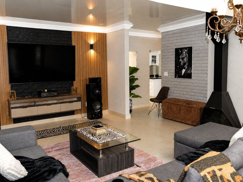 Spacious living room featuring a modern media wall with wood slat detailing, a suspended fireplace, and elegant crown molding with cove lighting.