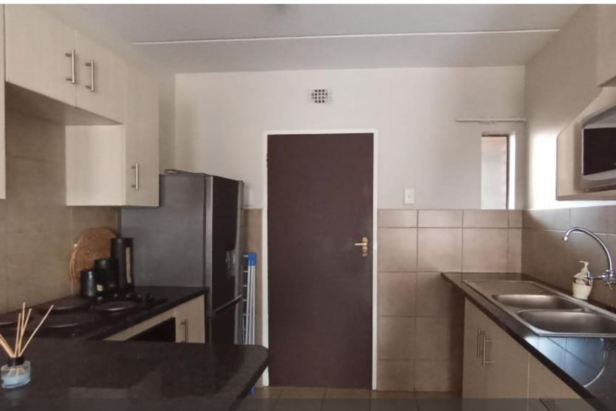 Functional kitchen featuring built-in cabinetry, granite countertops, a double basin sink, and integrated appliances including a hob and microwave.