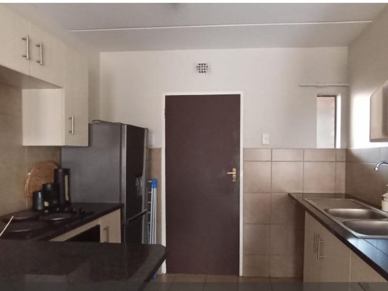 Functional kitchen featuring built-in cabinetry, granite countertops, a double basin sink, and integrated appliances including a hob and microwave.