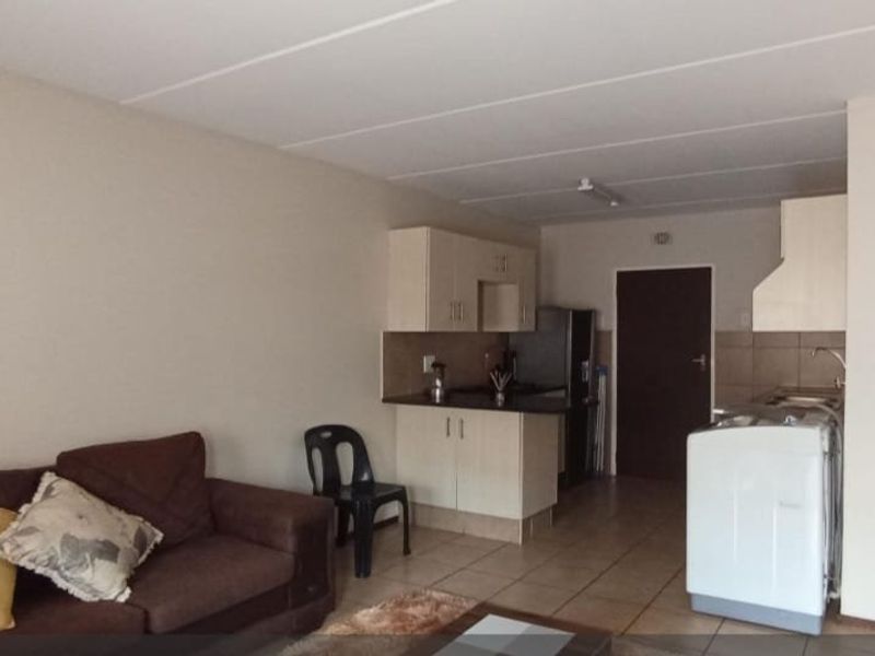 Open plan living area featuring a functional kitchen with built-in cabinetry and tiled flooring throughout.
