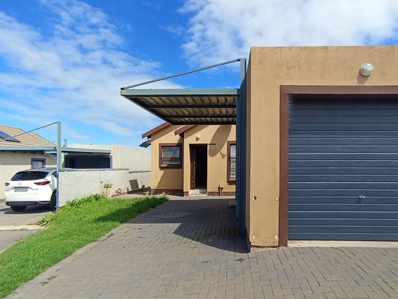 Front view of the property featuring a single garage, attached carport, and paved driveway area.