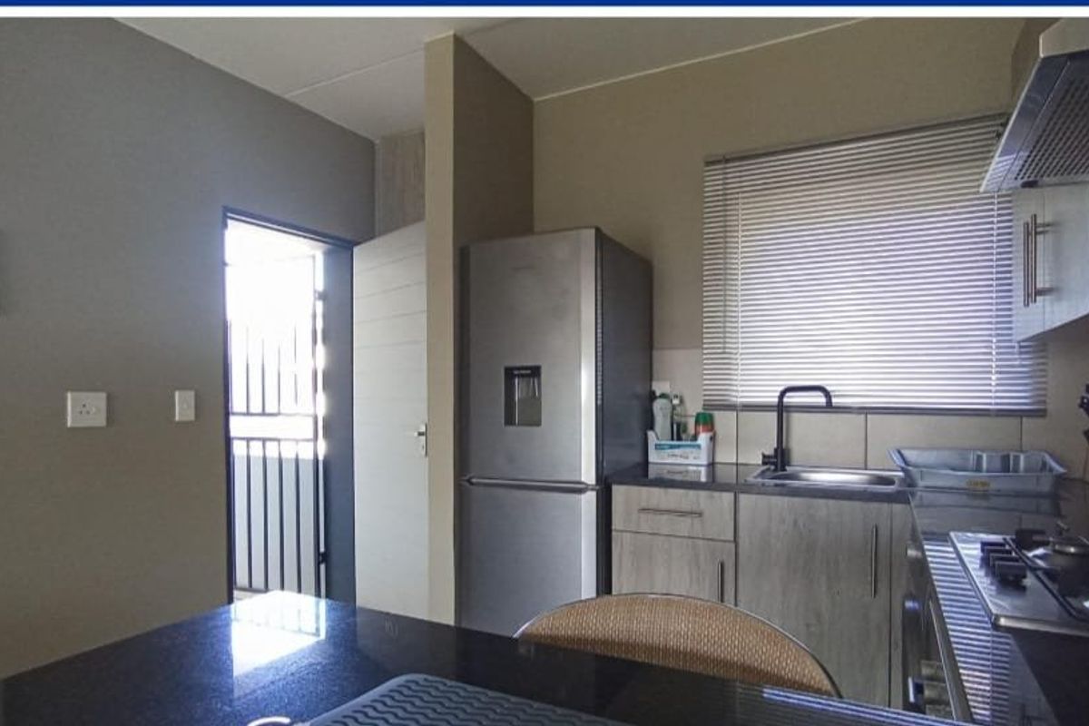 A functional kitchen featuring granite countertops, built-in cabinetry, a gas hob with extractor fan, and a modern black mixer tap.